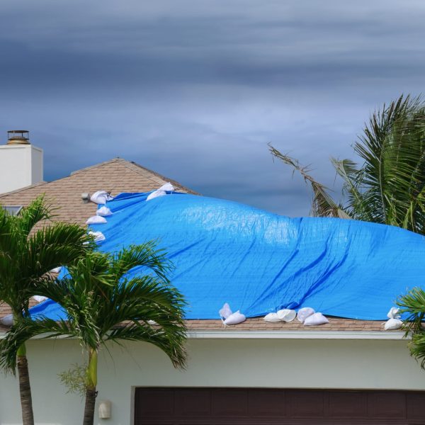 House covered with a weather proof blue roof tarp